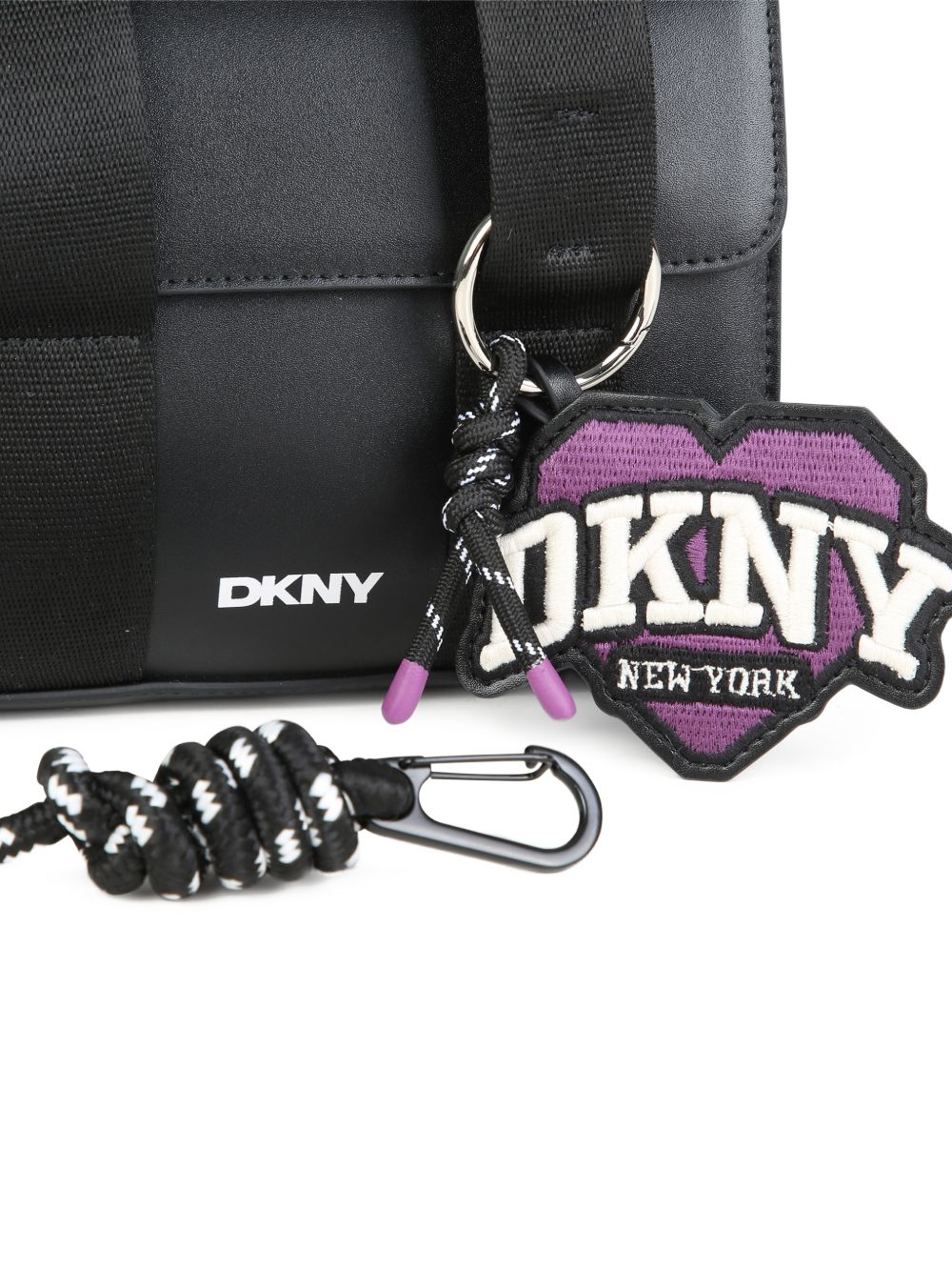 Handbag in simili con fantasia charms e stampa on davanti. Magnetic chiusura. Two possible ways to carry this bag : removable strap e handles. Colored fodera. Dimensions : 14.5x17.5x7cm. D62932 09B DKNY KIDS